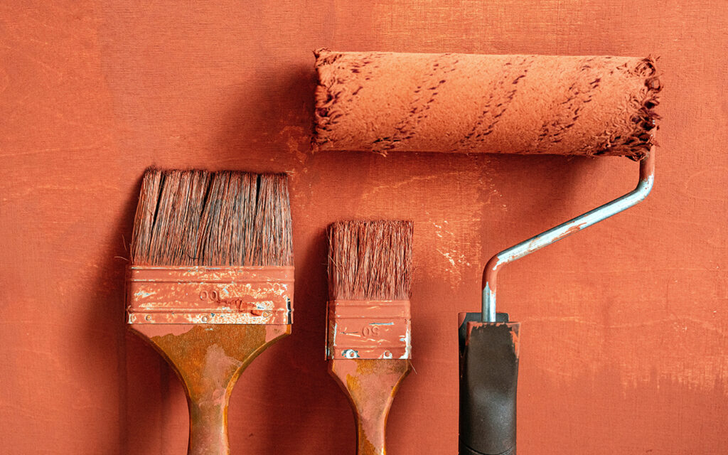 paint roller and brushes against an orange wall